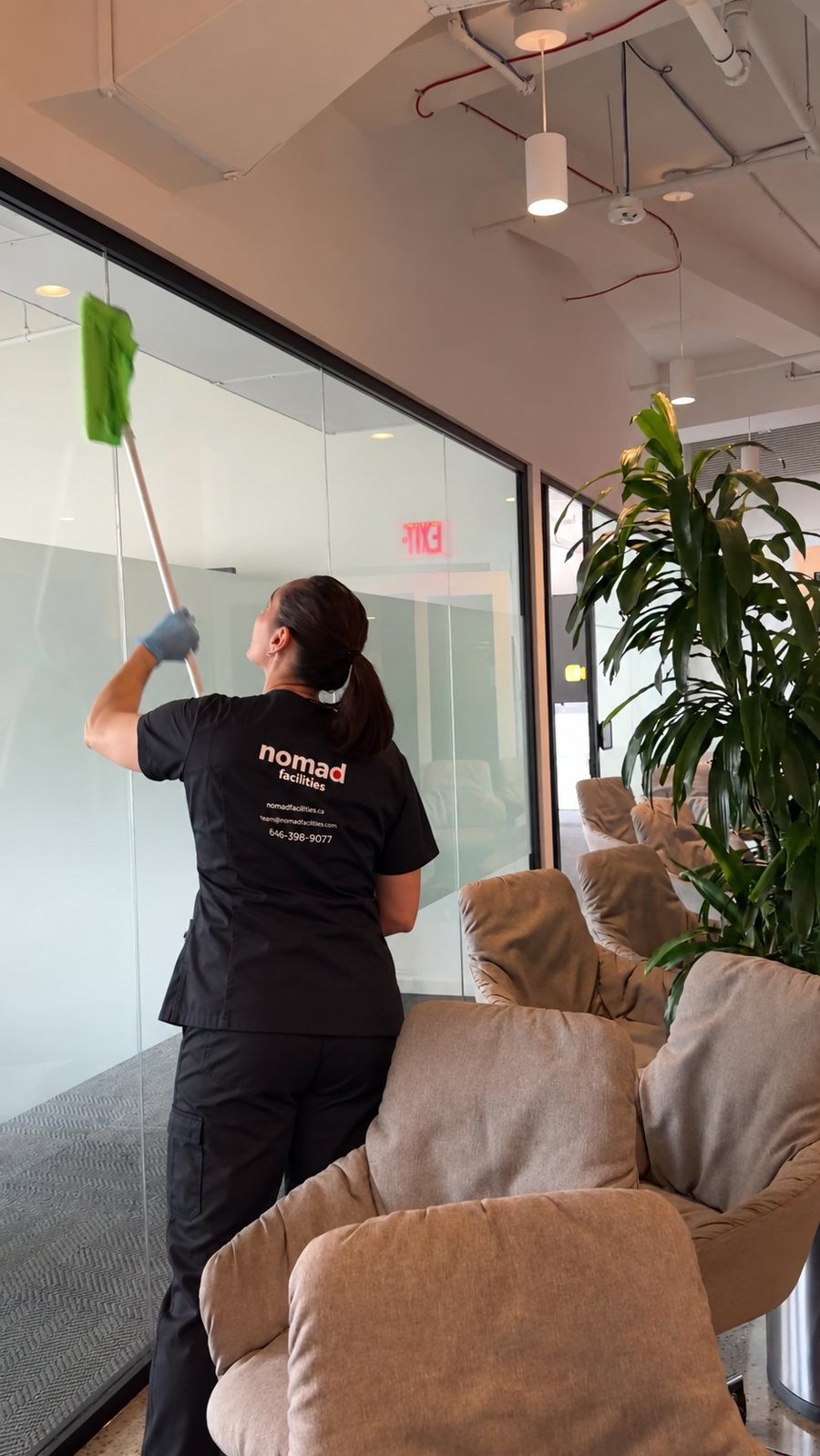 A Nomad Facilities day porter cleaning the glass walls of a client office